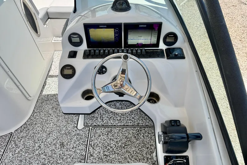 Slide: The Image of 2021 Twin Vee 240 GFX DC boat dashboard with steering wheel and navigation screens. - 14