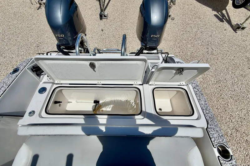 Slide: The Image of 2021 Twin Vee 240 GFX DC boat with open storage compartments and dual 150 engines. - 27