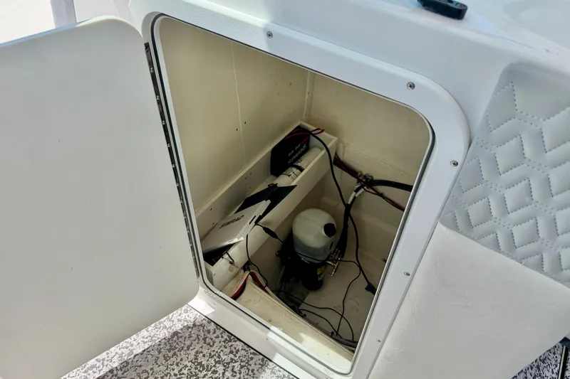 Slide: The Image of Open storage compartment in 2021 Twin Vee 240 GFX DC boat, showing interior wiring and equipment. - 29