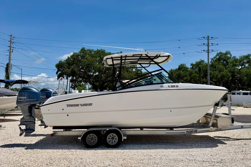Slide: The Image of 2021 Twin Vee 240 GFX DC boat on trailer, parked outdoors under clear blue sky. - 4