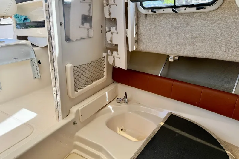 Slide: The Image of Interior of 2016 Grady-White Journey 258 boat, featuring a compact sink and seating area. - 24