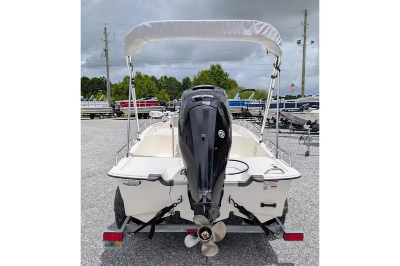 Slide: The Image of 2021 Mako Pro Skiff 17 CC boat with outboard motor and canopy, parked on gravel. - 3