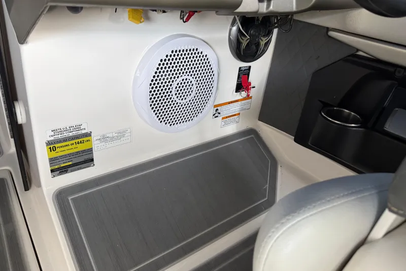 Slide: The Image of Interior of 2013 Regal 2100 Bowrider showing speaker, capacity label, and cup holder. - 15