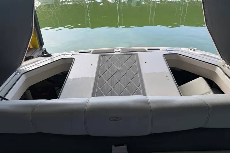 Slide: The Image of 2013 Regal 2100 Bowrider boat interior with cushioned seating and water view. - 19