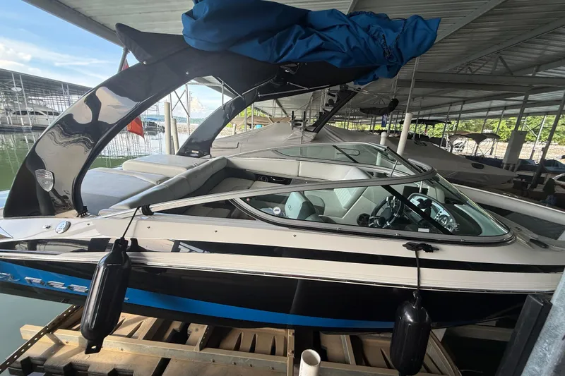Slide: The Image of 2013 Regal 2100 Bowrider boat docked under a covered marina. - 2