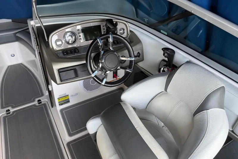 Slide: The Image of 2013 Regal 2100 Bowrider boat cockpit with steering wheel and dashboard controls. - 26