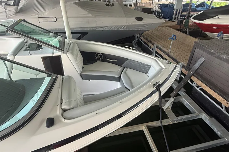 Slide: The Image of 2013 Regal 2100 Bowrider boat docked, featuring sleek white seating and windshield. - 3
