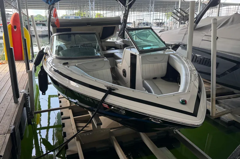 Slide: The Image of 2013 Regal 2100 Bowrider boat docked in a marina, featuring sleek design and spacious seating. - 8