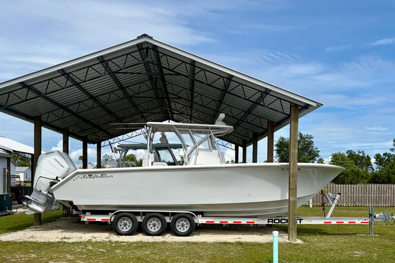 Slide: The Image of 2024 SeaHunter 31 Tournament boat on trailer under metal canopy, side view. - 2