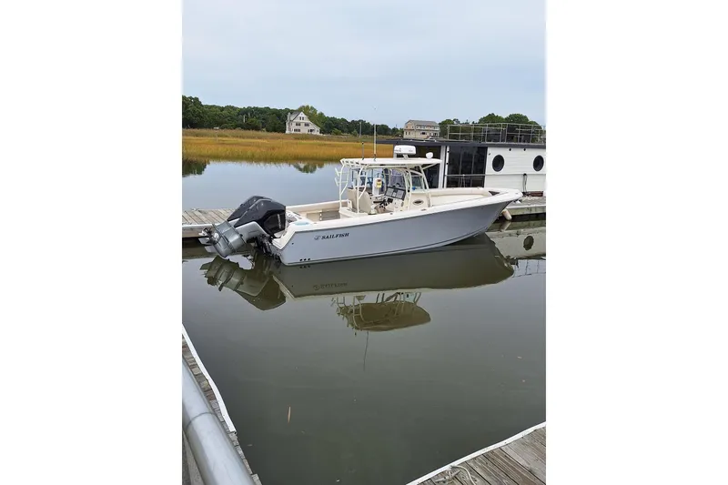 Slide: The Image of 2022 Sailfish 320 CC boat docked in calm waters, showcasing sleek design and twin engines. - 2