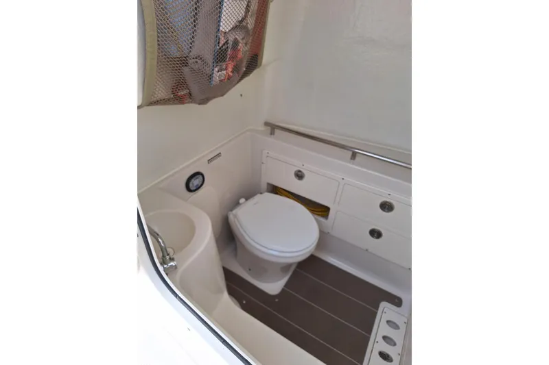 Slide: The Image of Interior of 2022 Sailfish 320 CC boat featuring a compact marine toilet and sink. - 5