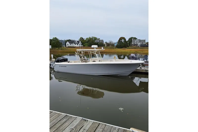 Slide: The Image of 2022 Sailfish 320 CC boat docked in a serene marina setting. - 8