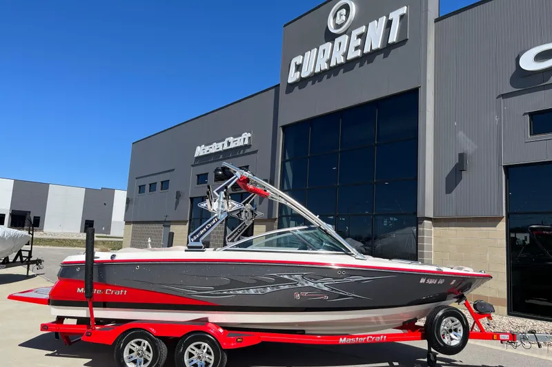 The Image of 2007 MasterCraft X-15 boat on trailer outside dealership, featuring sleek design and vibrant colors. - 0