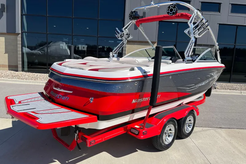 Slide: The Image of 2007 MasterCraft X-15 boat in red and white, parked on a trailer outside a building. - 3