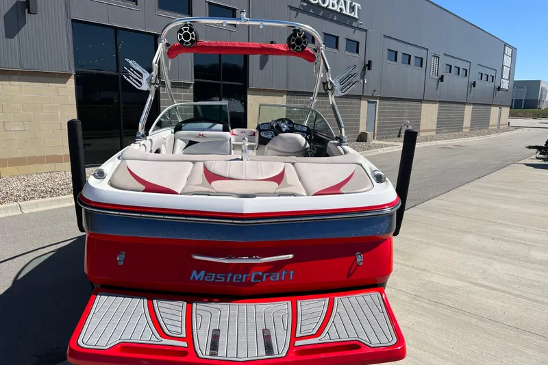 Slide: The Image of 2007 MasterCraft X-15 boat with red and white interior, parked near a modern building. - 8