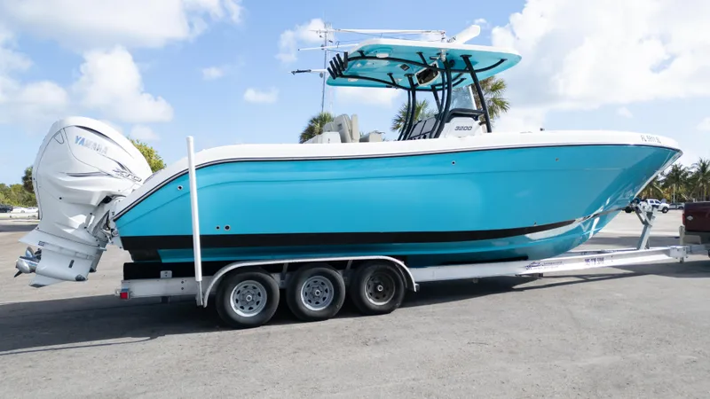 Slide: The Image of 2019 Century 3200 Center Console boat on trailer, vibrant blue hull, dual outboard engines. - 43