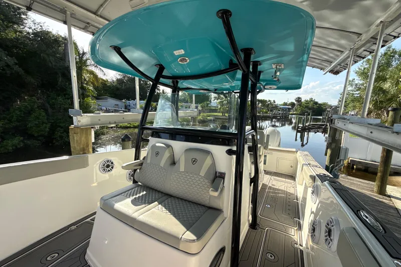 Slide: The Image of 2019 Century 3200 Center Console boat interior with seating and console, docked by a scenic waterfront. - 64