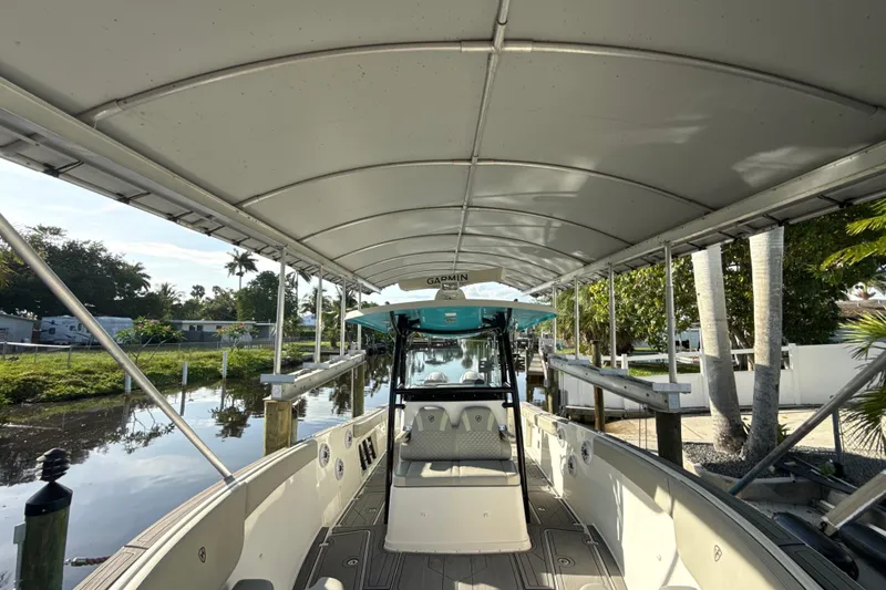 Slide: The Image of 2019 Century 3200 Center Console boat docked under canopy, surrounded by lush greenery. - 65