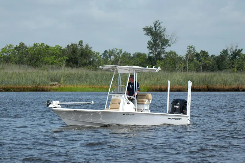 The Image of 2018 Sportsman Tournament 214 Bay Boat cruising on a calm river with lush greenery. - 1