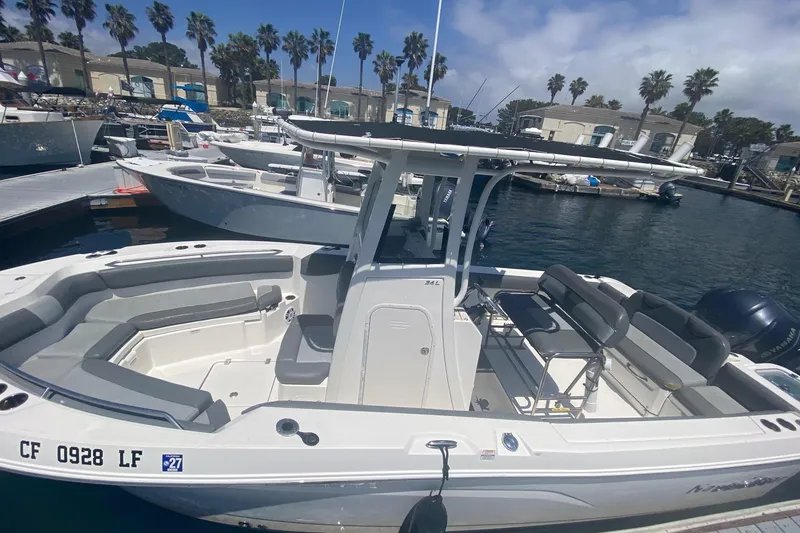 Slide: The Image of 2023 NauticStar 242L Offshore boat docked at marina with seating and T-top. - 10