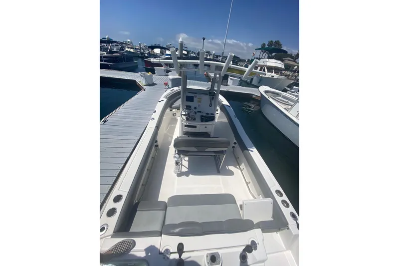 Slide: The Image of 2023 NauticStar 242L Offshore boat docked at marina, showcasing spacious interior and helm. - 11