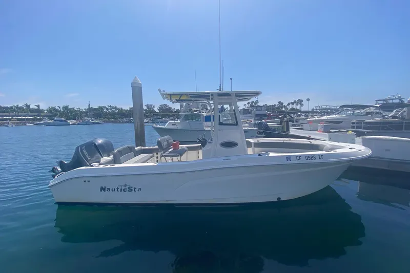 The Image of 2023 NauticStar 242L Offshore boat docked in a sunny marina. - 7