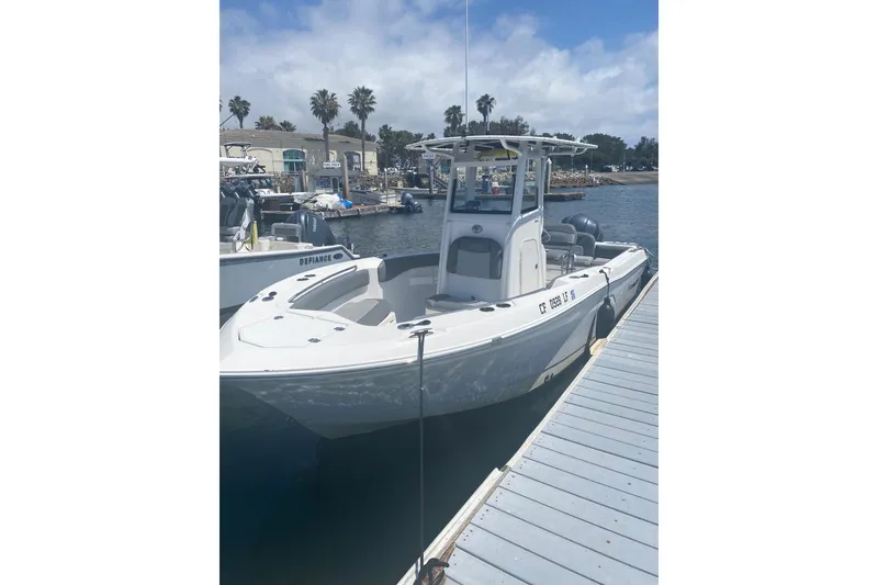 Slide: The Image of 2023 NauticStar 242L Offshore boat docked at a marina under a partly cloudy sky. - 9