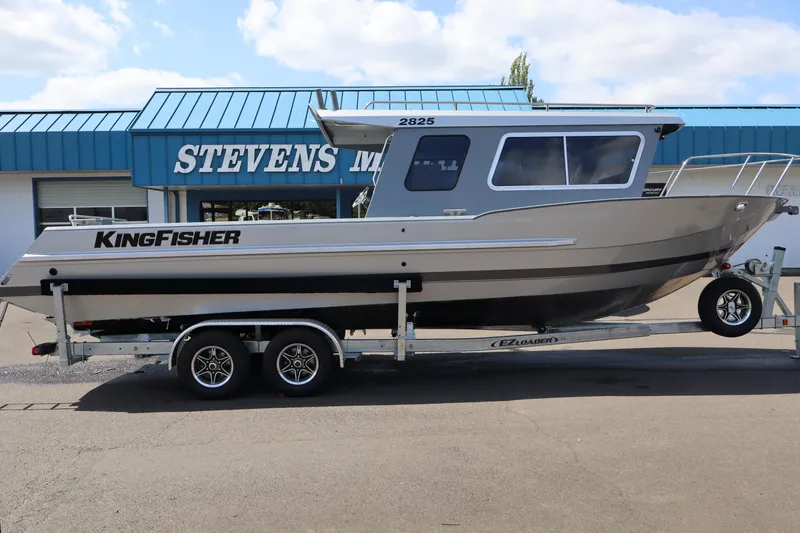 The Image of 2026 KingFisher 2825 Coastal Express boat on trailer outside Stevens Marine dealership. - 1