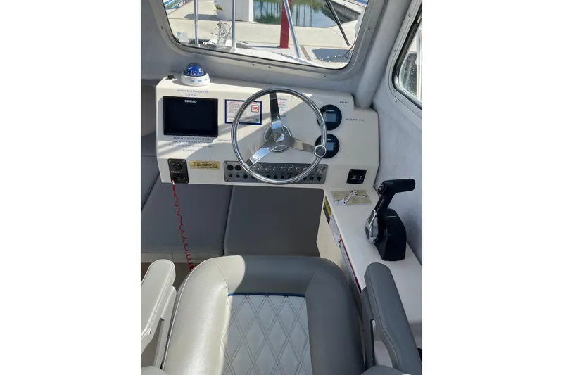 Slide: The Image of 2023 Defiance Admiral 220 EX boat helm with steering wheel, controls, and navigation display. - 17