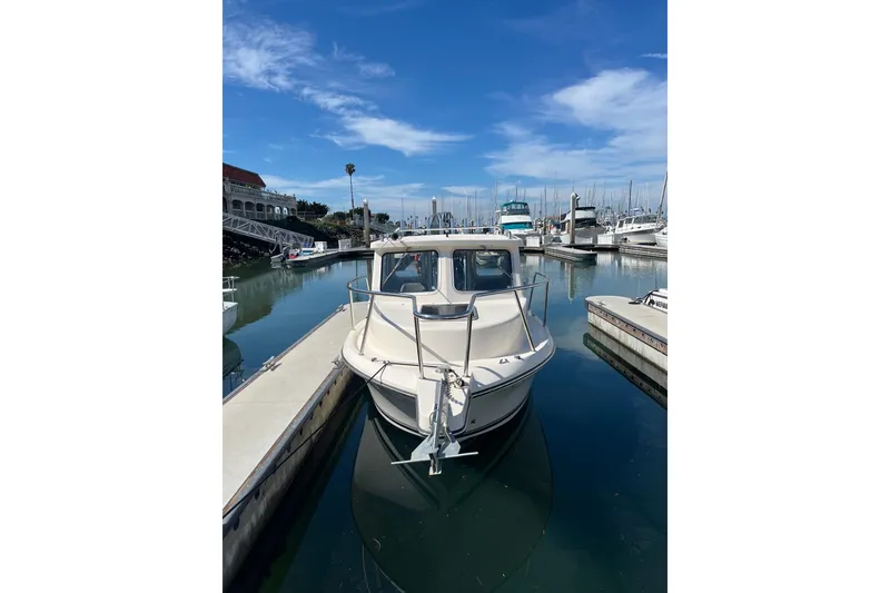 Slide: The Image of 2023 Defiance Admiral 220 EX boat docked in a marina under a clear blue sky. - 2