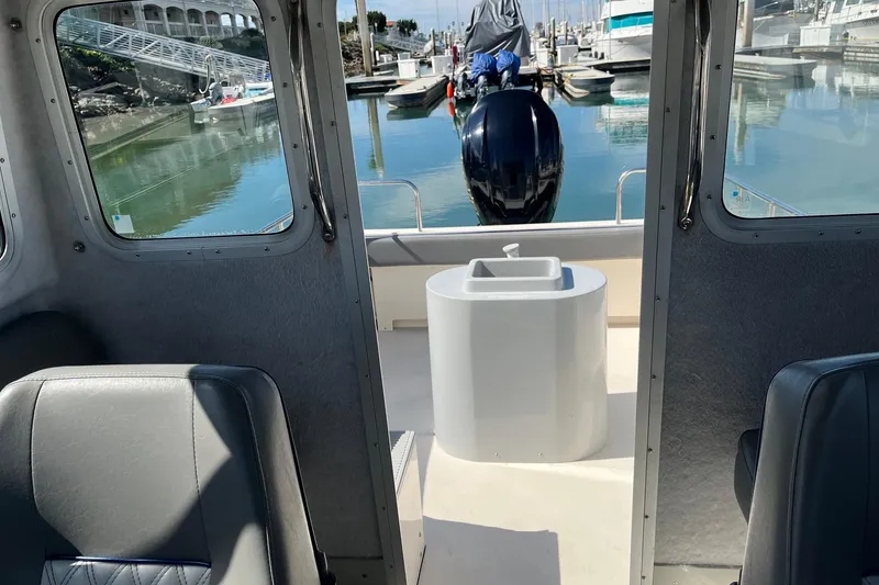 Slide: The Image of Interior view of 2023 Defiance Admiral 220 EX boat at marina, showcasing seating and engine. - 27