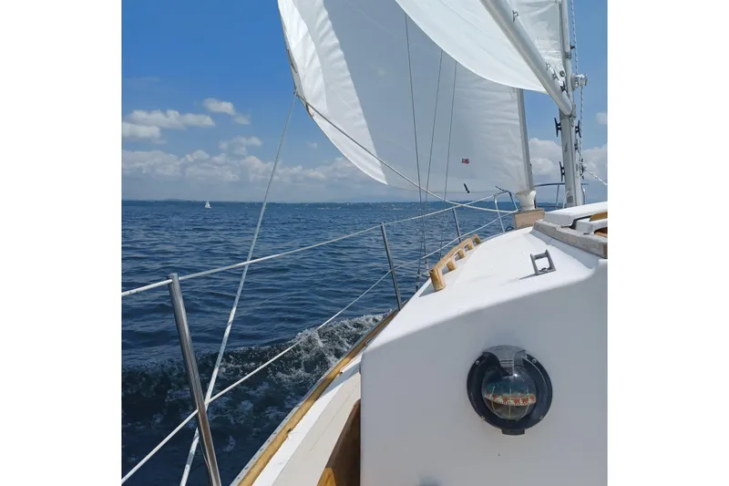 Slide: The Image of 1982 Cape Dory sailboat navigating open waters under clear blue skies. - 3