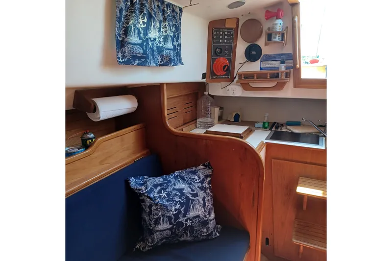 Slide: The Image of Interior of a 1982 Cape Dory boat with nautical-themed decor and compact kitchen area. - 5
