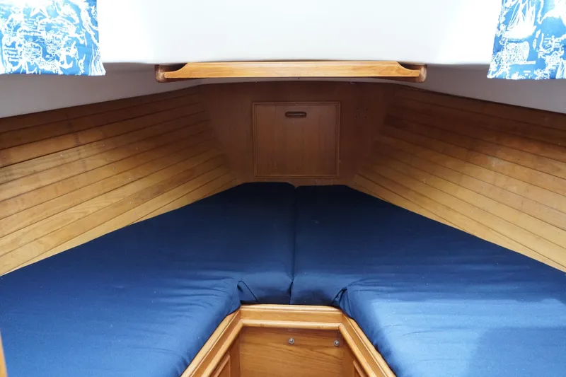 Slide: The Image of 1982 Cape Dory boat interior with blue cushions and wooden paneling. - 6
