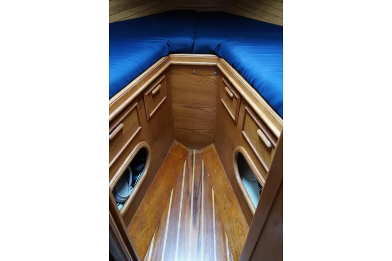 Slide: The Image of 1982 Cape Dory boat interior with wooden cabinetry and blue cushions. - 7