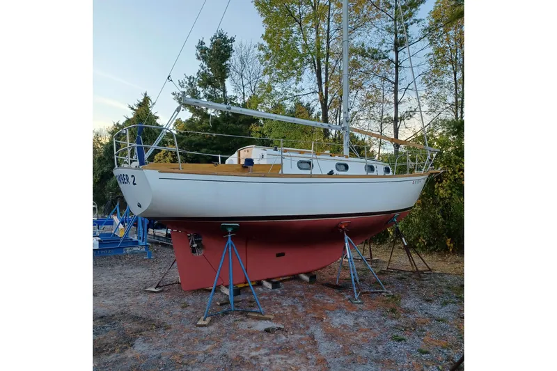 Slide: The Image of 1982 Cape Dory sailboat on stands, surrounded by trees, ready for maintenance. - 9