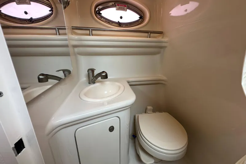 Slide: The Image of 2008 Sea Ray Sundancer 260 bathroom with sink, toilet, and oval windows. - 19