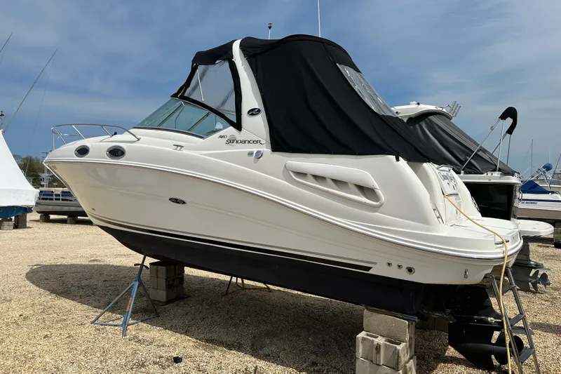Slide: The Image of 2008 Sea Ray Sundancer 260 boat on dry dock, covered, with clear sky background. - 20