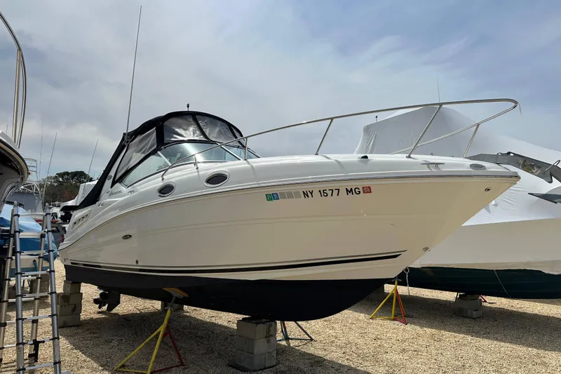 Slide: The Image of 2008 Sea Ray Sundancer 260 boat on stands, with black canopy, parked outdoors. - 21