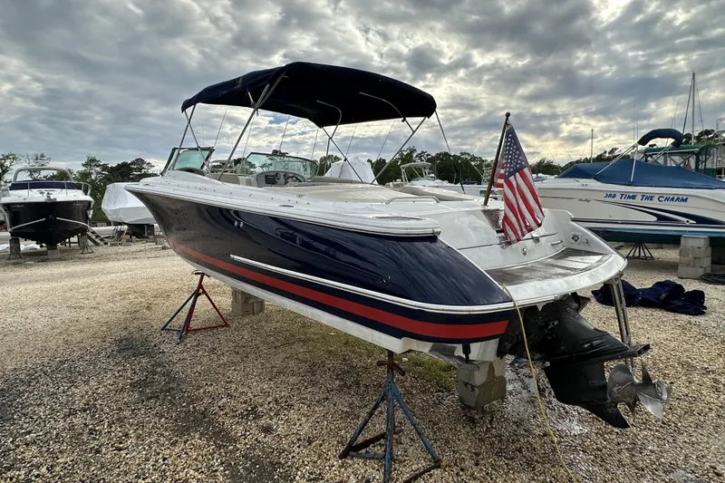 Slide: The Image of 2005 Chris-Craft Launch 28 boat with American flag, displayed on stands under cloudy sky. - 21