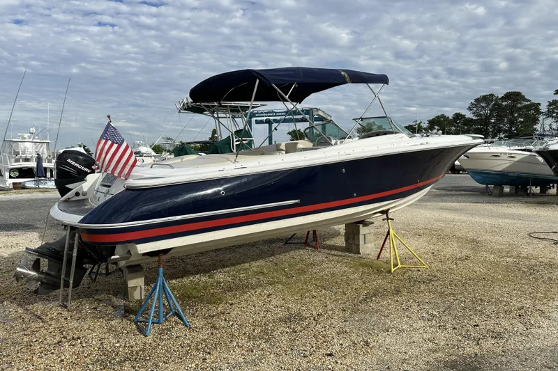 Slide: The Image of 2005 Chris-Craft Launch 28 boat on stands, with American flag, under cloudy sky. - 22