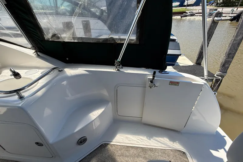 Slide: The Image of 2002 Sea Ray Sundancer 260 boat interior with seating and storage, docked at marina. - 10