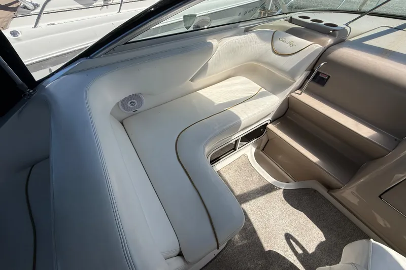 Slide: The Image of Interior seating of 2002 Sea Ray Sundancer 260 boat, featuring white upholstery and integrated speaker. - 14