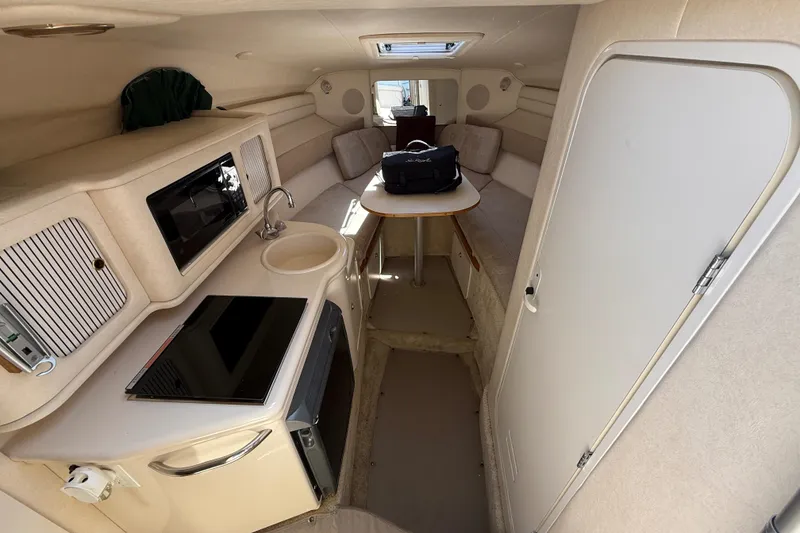 Slide: The Image of Interior of 2002 Sea Ray Sundancer 260 boat, featuring kitchenette and seating area. - 21
