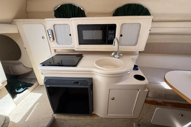 Slide: The Image of 2002 Sea Ray Sundancer 260 cabin kitchen with sink, microwave, and mini-fridge. - 26