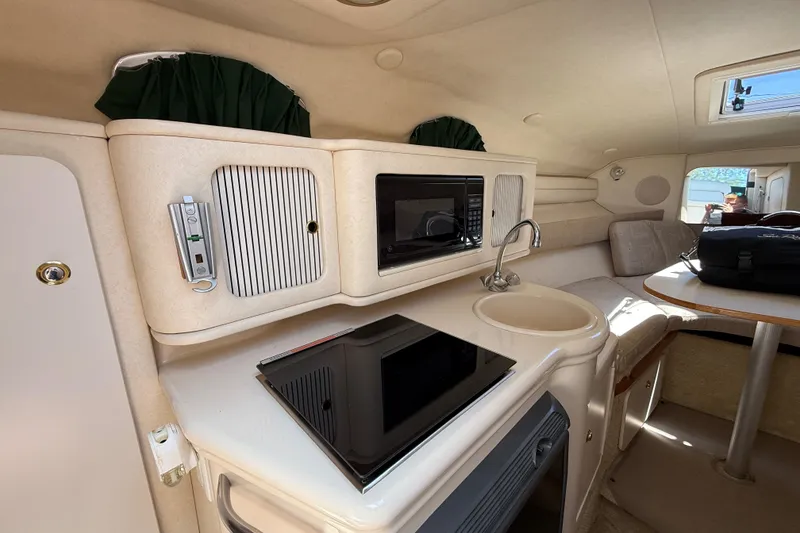 Slide: The Image of Interior of 2002 Sea Ray Sundancer 260 boat with kitchenette and seating area. - 27