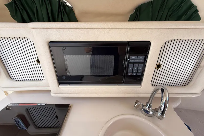 Slide: The Image of Interior of a 2002 Sea Ray Sundancer 260 featuring a microwave, sink, and storage cabinets. - 31
