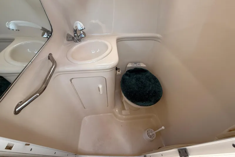 Slide: The Image of Compact bathroom in a 2002 Sea Ray Sundancer 260 boat, featuring a sink and toilet. - 33