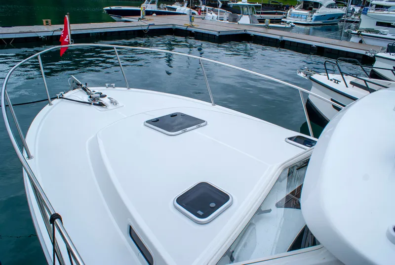 Slide: The Image of A modern boat with a white deck and several hatches is docked at a marina. - 43