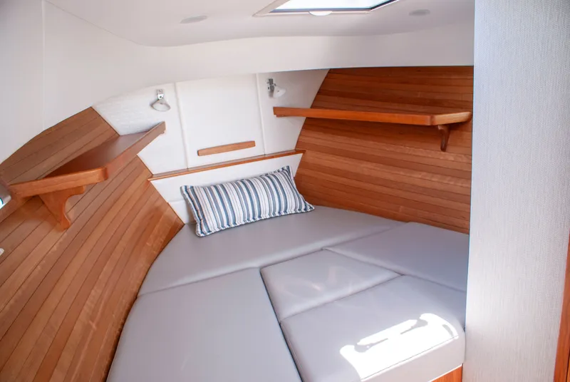 Slide: The Image of The 2027 MJM Yachts 38R cabin features a cozy bed with wooden walls and shelves. - 39